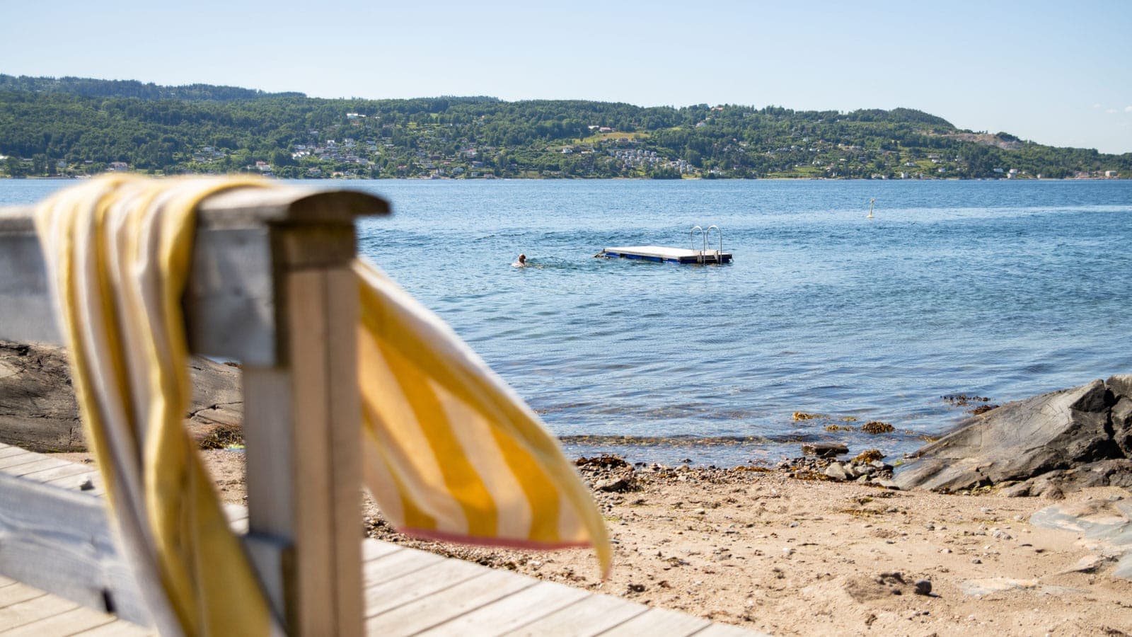 Strand med gult strandhåndkle som blafrer i vinden