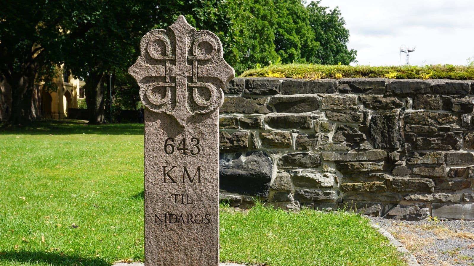 Pilegrimsleden viser vei til Nidaros. Steinvegg i bakgrunnen