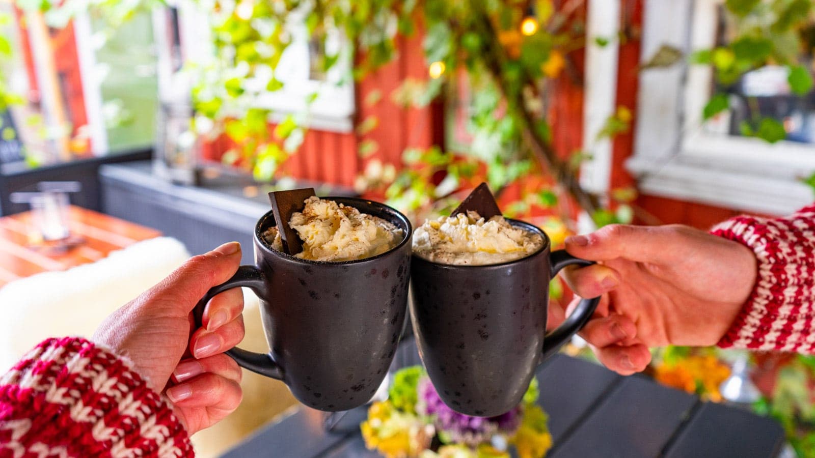 To hender som holder kakao med krem på en uteservering