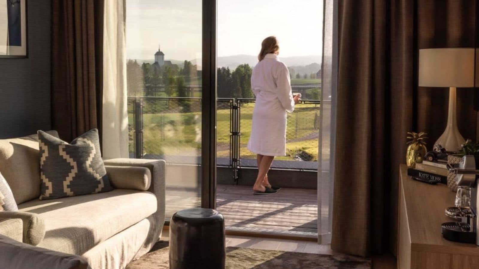 dame som ser ut over et landskap fra en balkong på et hotellrom