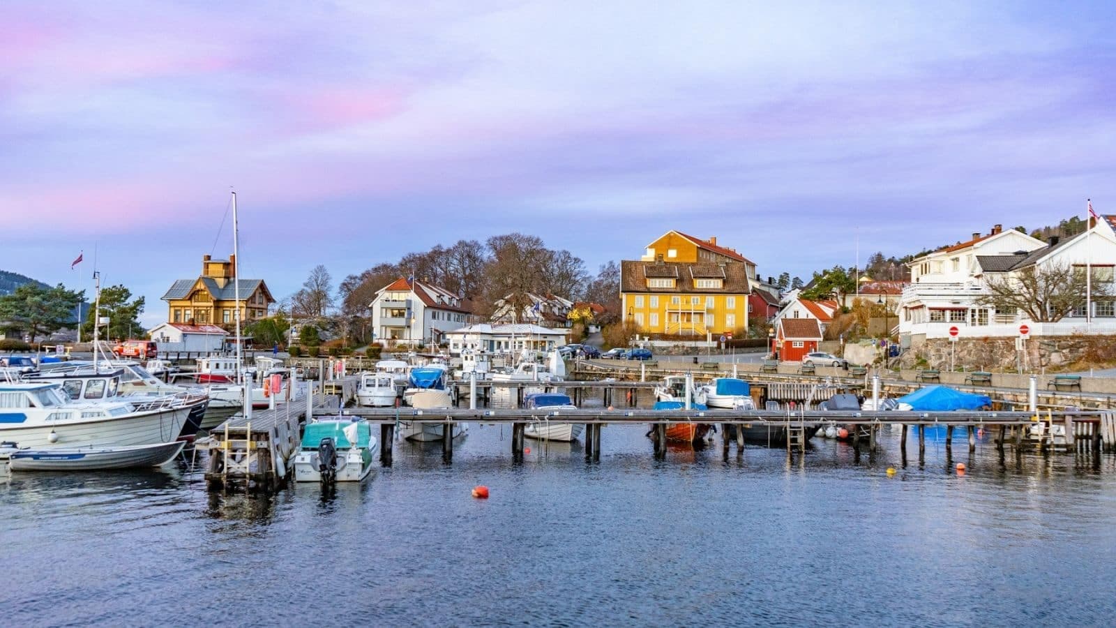 Havne i solnedgang med båter,brygge og hus i bakgrunnen